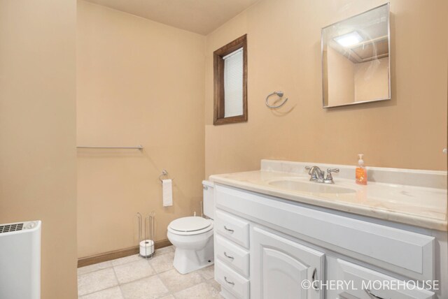 3390 E Baseline Rd, White Cloud, MI 49349 - bathroom featuring radiator heating unit, tile patterned floors, vanity, baseboards, and toilet