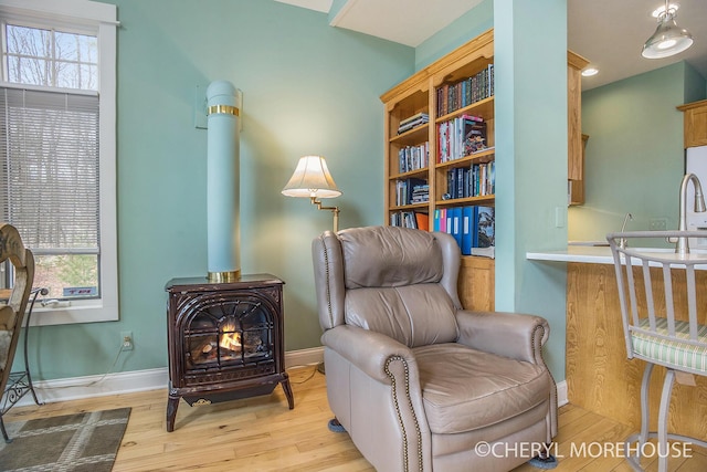 3390 E Baseline Rd, White Cloud, MI 49349 - living area with light wood-style flooring, baseboards, and a wood stove