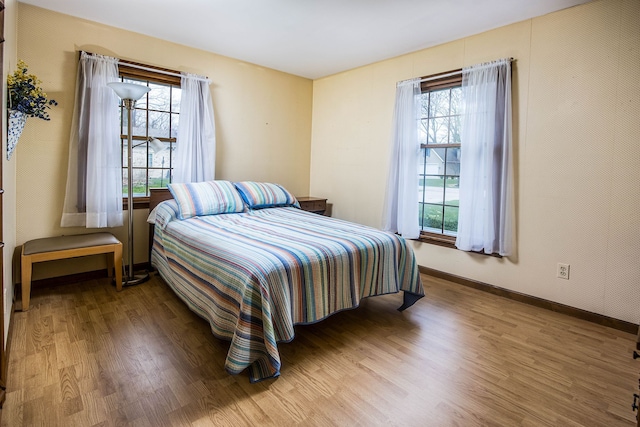 bedroom with baseboards, multiple windows, and wood finished floors