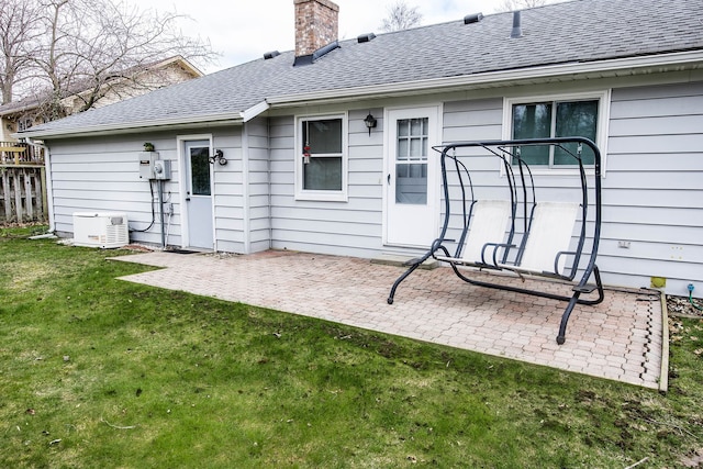 rear view of property with a patio, a chimney, a lawn, fence, and a shingled roof
