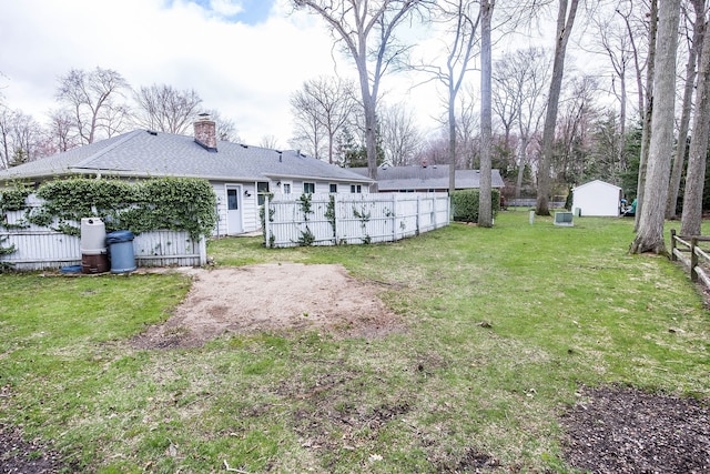 back of property with a yard, fence, a chimney, and an outbuilding
