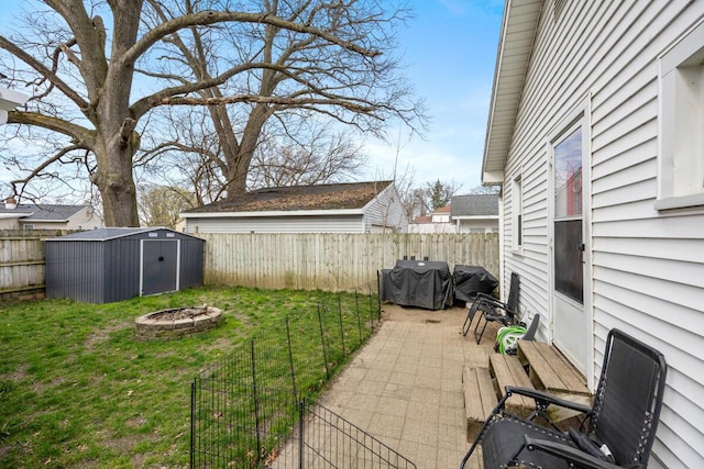 view of yard featuring a fenced backyard, a storage shed, an outbuilding, and an outdoor fire pit