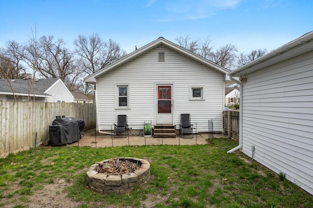 rear view of property featuring a fenced backyard, entry steps, a patio area, a yard, and an outdoor fire pit