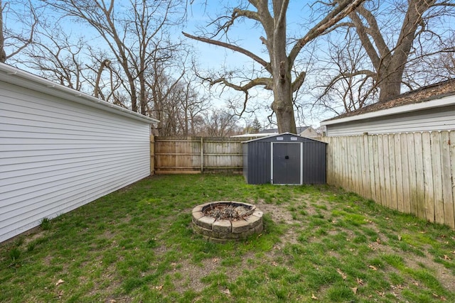 view of yard with a fenced backyard, an outbuilding, a storage shed, and a fire pit