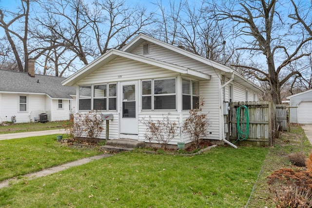 bungalow-style house with fence, a sunroom, a front yard, and central AC unit