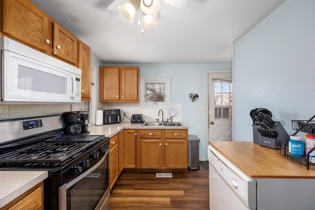 kitchen with dark wood-style floors, a sink, visible vents, a ceiling fan, and white appliances