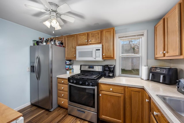 kitchen featuring light countertops, a sink, dark wood-type flooring, and appliances with stainless steel finishes
