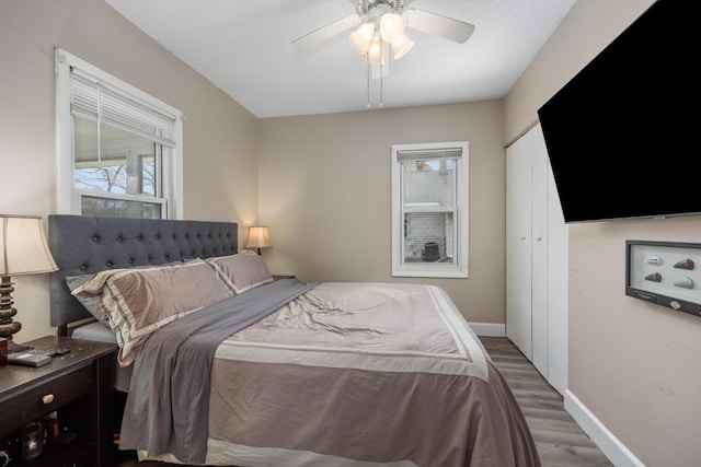 bedroom featuring baseboards, a ceiling fan, wood finished floors, and a closet