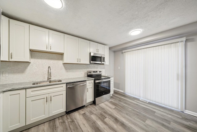 35333 Stellwagen St, Wayne, MI 48184 - kitchen featuring light wood finished floors, a sink, a textured ceiling, appliances with stainless steel finishes, and white cabinetry