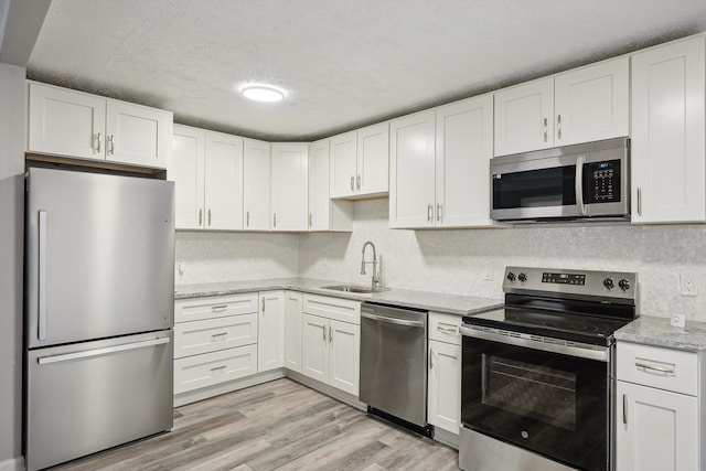 35333 Stellwagen St, Wayne, MI 48184 - kitchen featuring light stone counters, a sink, light wood-type flooring, stainless steel appliances, and white cabinetry