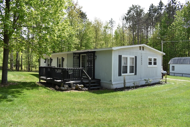 7885 W Fox Rd, Mears, MI 49436 - manufactured / mobile home featuring a front lawn, a wooden deck, and view of wooded area