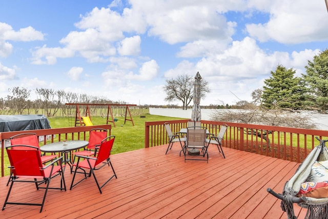 wooden deck with a yard, outdoor dining area, fence, and a playground