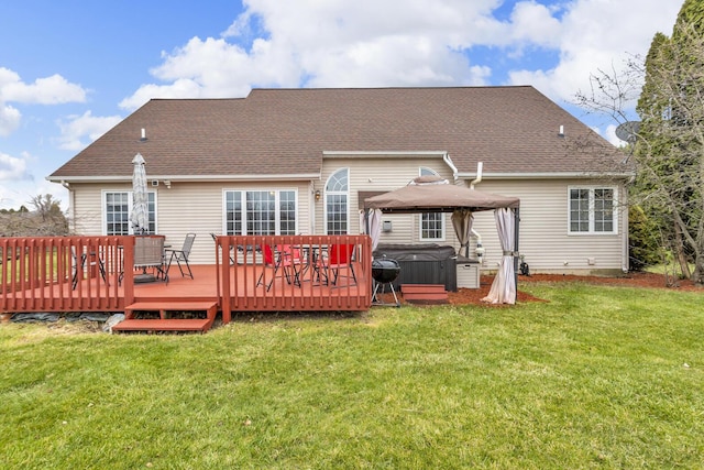 rear view of house featuring a lawn, a wooden deck, a gazebo, and a hot tub