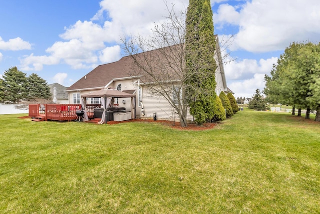 back of property with a lawn, a wooden deck, a gazebo, and a hot tub