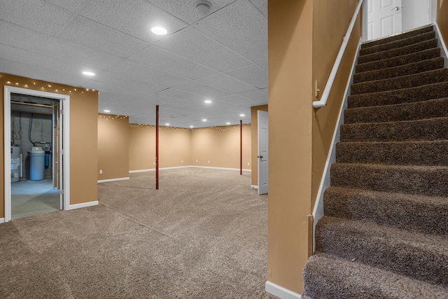 finished basement featuring stairs, water heater, carpet floors, baseboards, and recessed lighting