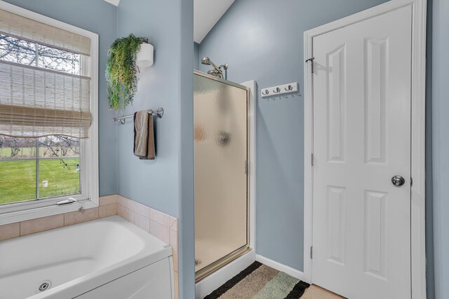 bathroom with a bath, baseboards, and a stall shower