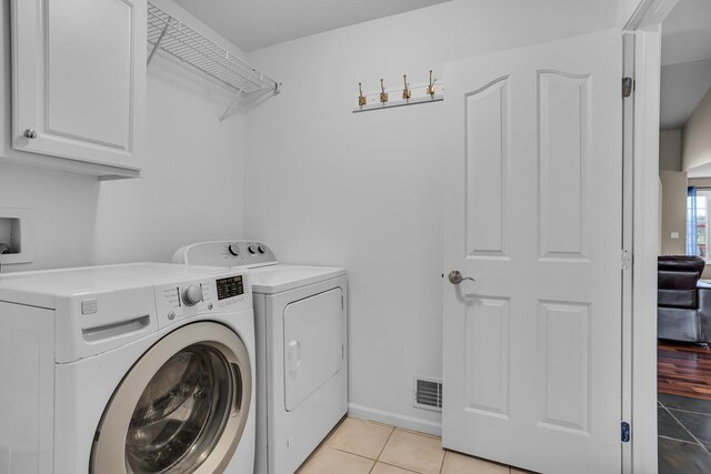 washroom with washer and dryer, cabinet space, light tile patterned flooring, and visible vents