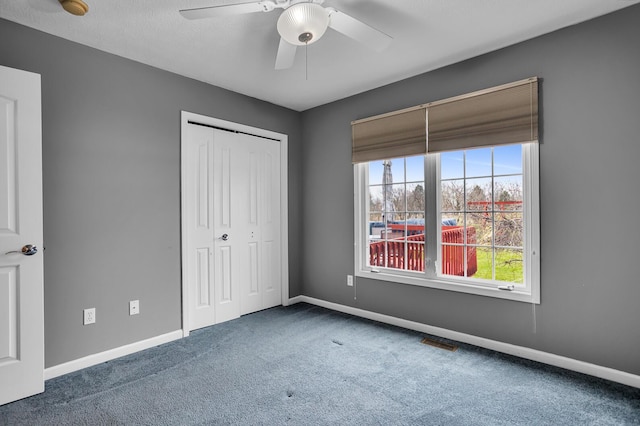 unfurnished bedroom featuring baseboards, visible vents, carpet, a ceiling fan, and a closet