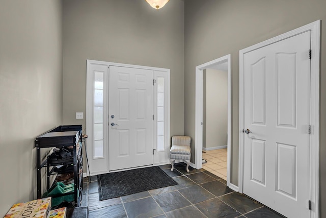 foyer entrance featuring baseboards and a towering ceiling