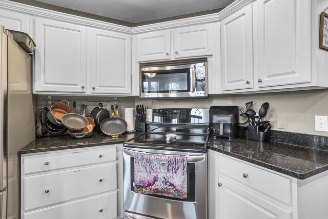 kitchen with dark stone countertops, white cabinetry, and appliances with stainless steel finishes