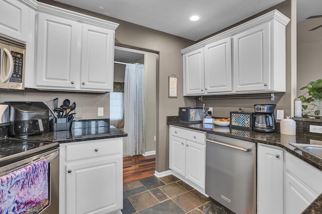 kitchen featuring white cabinets, appliances with stainless steel finishes, and stone finish floor