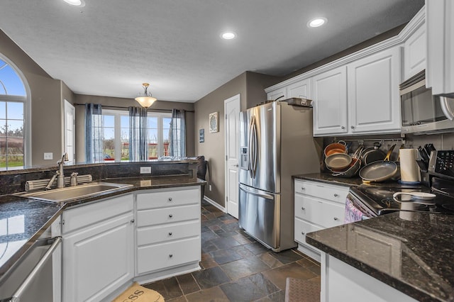 kitchen featuring stone tile floors, stainless steel appliances, a sink, and a wealth of natural light