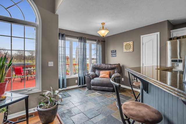 sitting room with baseboards, stone tile floors, and visible vents