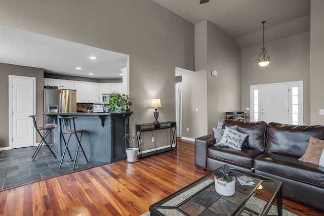 living area featuring baseboards, high vaulted ceiling, and dark wood-type flooring
