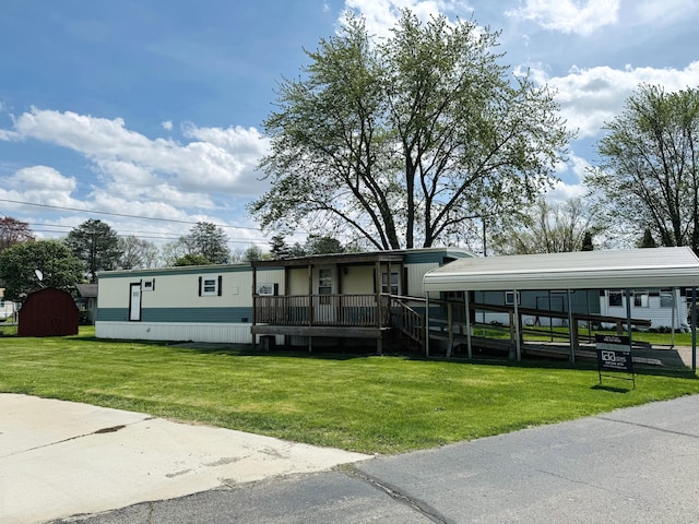 manufactured / mobile home with a porch, a front yard, and a detached carport