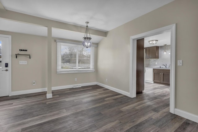 808 Longfellow Ave, Jackson, MI 49202 - unfurnished dining area featuring dark wood-type flooring, visible vents, baseboards, and an inviting chandelier
