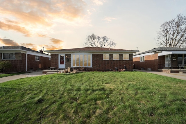 view of front facade with a lawn and brick siding