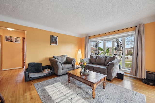 living area with light wood finished floors, visible vents, and a textured ceiling