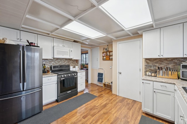 kitchen featuring decorative backsplash, white cabinetry, light wood-style flooring, coffered ceiling, and appliances with stainless steel finishes