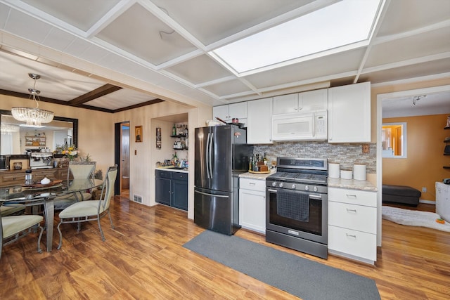 kitchen with backsplash, appliances with stainless steel finishes, light wood-style floors, and white cabinetry