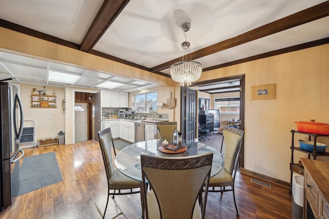 dining area featuring visible vents, wood finished floors, a healthy amount of sunlight, and an inviting chandelier