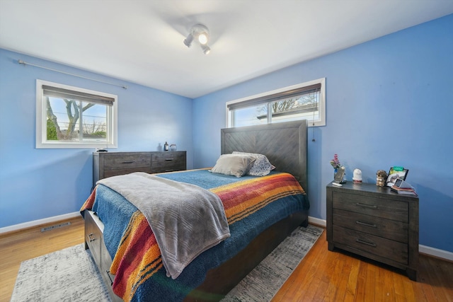 bedroom featuring baseboards, wood finished floors, and visible vents