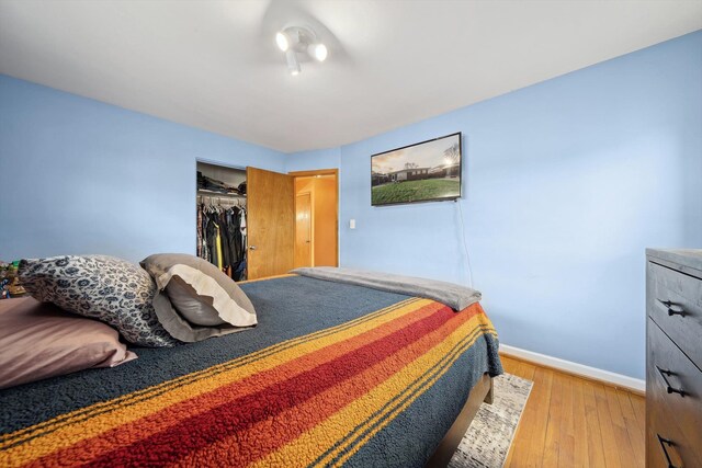 bedroom with hardwood / wood-style flooring, baseboards, and a closet