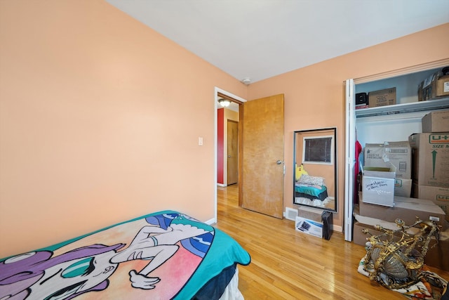 bedroom with baseboards, wood finished floors, and a closet