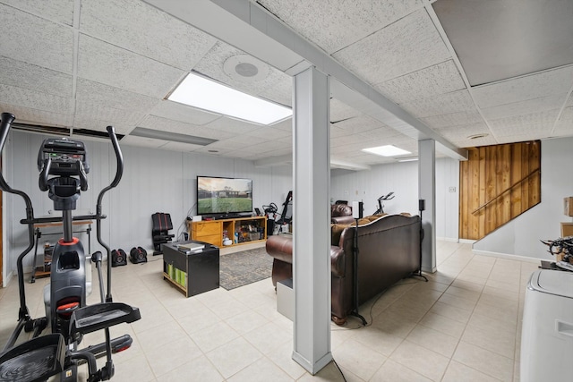 exercise area featuring wooden walls, a paneled ceiling, and light tile patterned floors