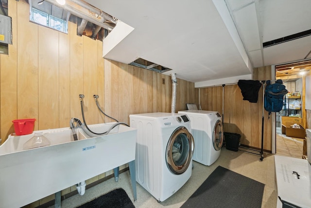 laundry room featuring washing machine and dryer, wood walls, a sink, and laundry area