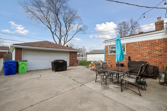 view of patio / terrace featuring an outbuilding, fence, a garage, grilling area, and outdoor dining space