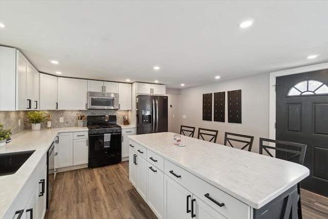 kitchen with stainless steel appliances, a center island, recessed lighting, backsplash, and dark wood-type flooring