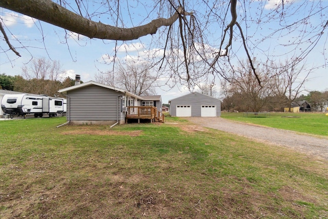 exterior space featuring a chimney, an outdoor structure, a yard, a garage, and a wooden deck