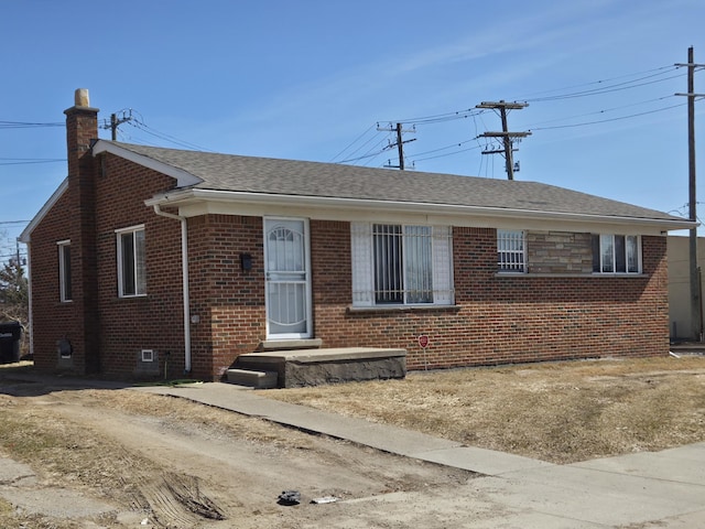 view of front of home featuring brick siding, a shingled roof, and a chimney