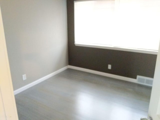empty room with baseboards, wood finished floors, and visible vents
