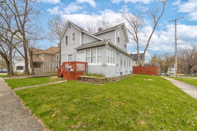 view of front of home featuring fence, a chimney, and a front lawn