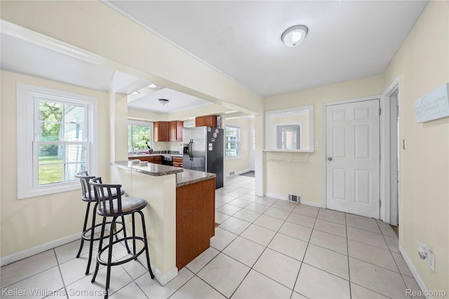 21700 W 13 Mile Rd, Beverly Hills, MI 48025 - kitchen with a peninsula, a breakfast bar, baseboards, stainless steel fridge with ice dispenser, and light tile patterned floors