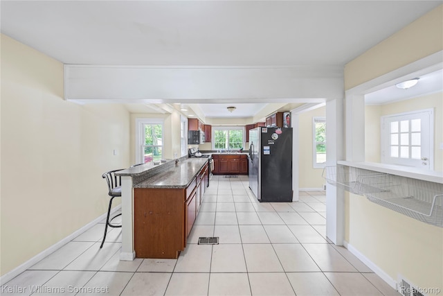 21700 W 13 Mile Rd, Beverly Hills, MI 48025 - kitchen with appliances with stainless steel finishes, a kitchen bar, baseboards, a peninsula, and light tile patterned floors