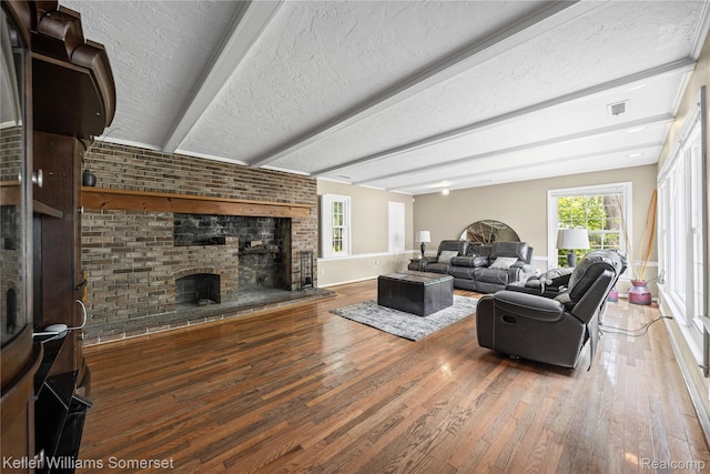 21700 W 13 Mile Rd, Beverly Hills, MI 48025 - living room with wood finished floors, a brick fireplace, baseboards, beamed ceiling, and a textured ceiling