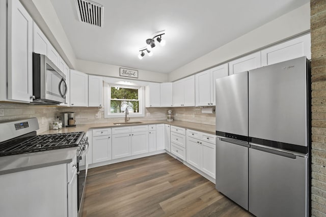 kitchen featuring a sink, white cabinets, stainless steel appliances, backsplash, and visible vents